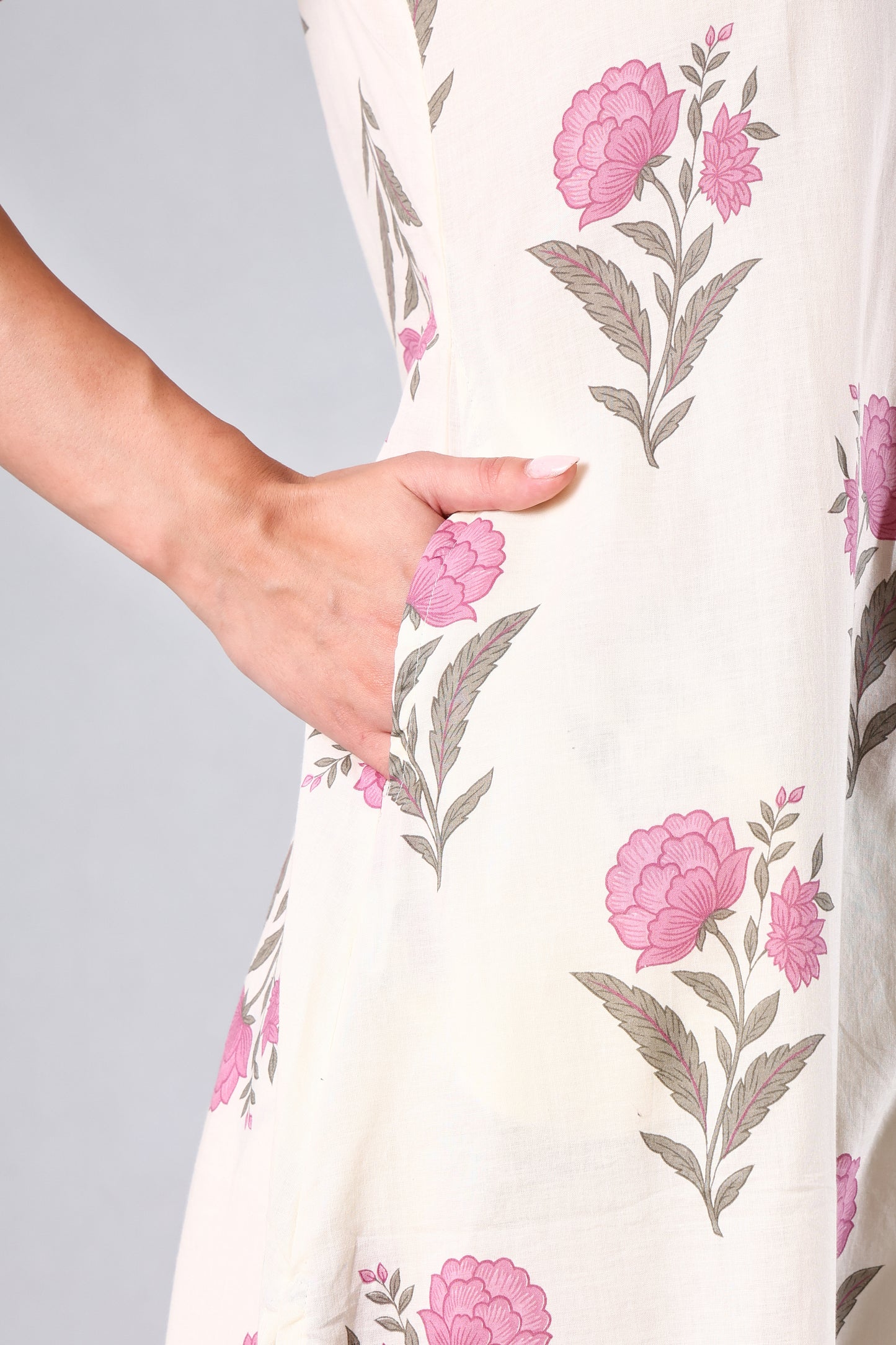 Close-up of a floral-patterned dress with Pink flowers and green leaves on a plain background.