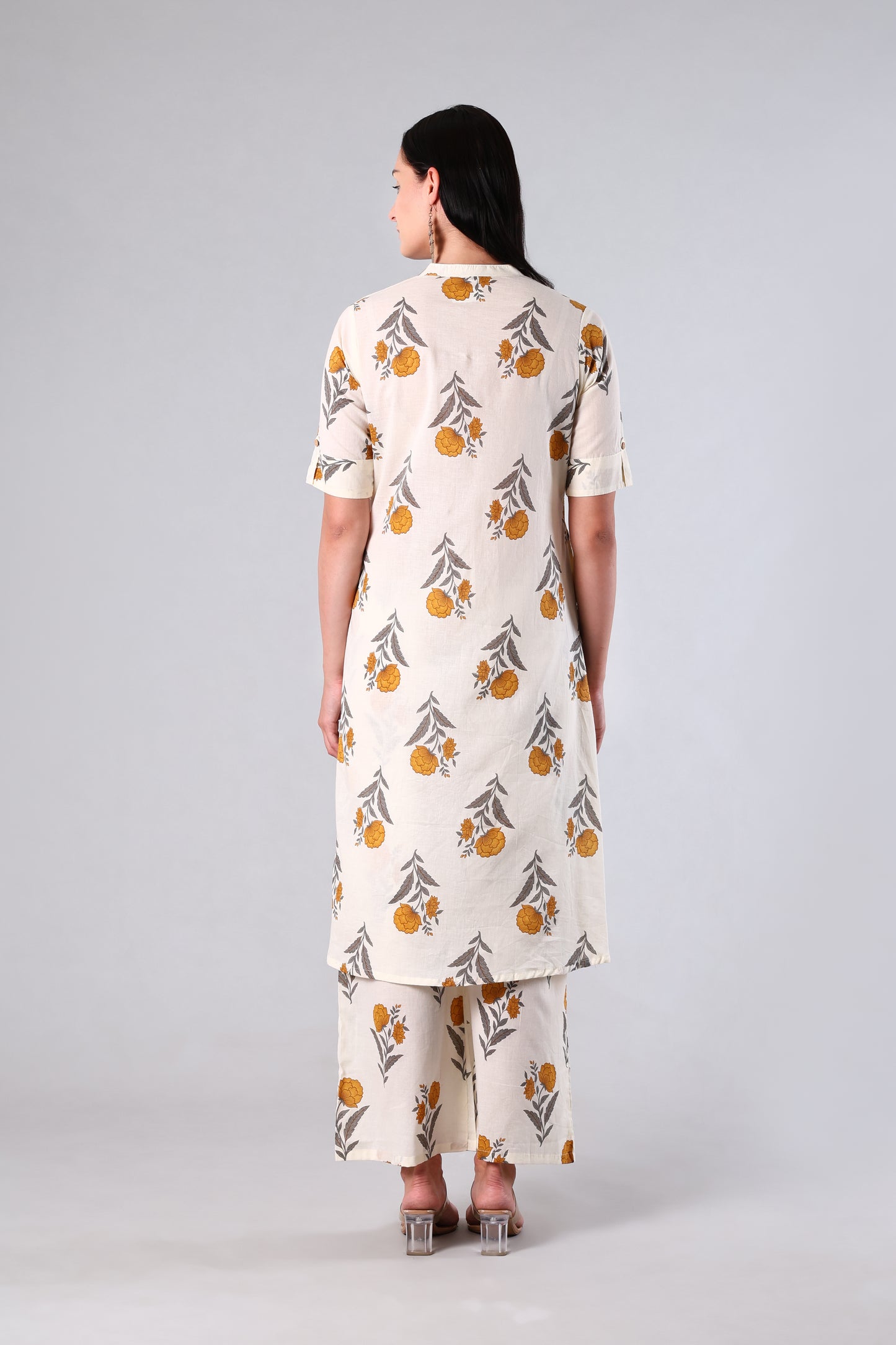 Woman wearing a white outfit with Yellow and black patterns on a gray background