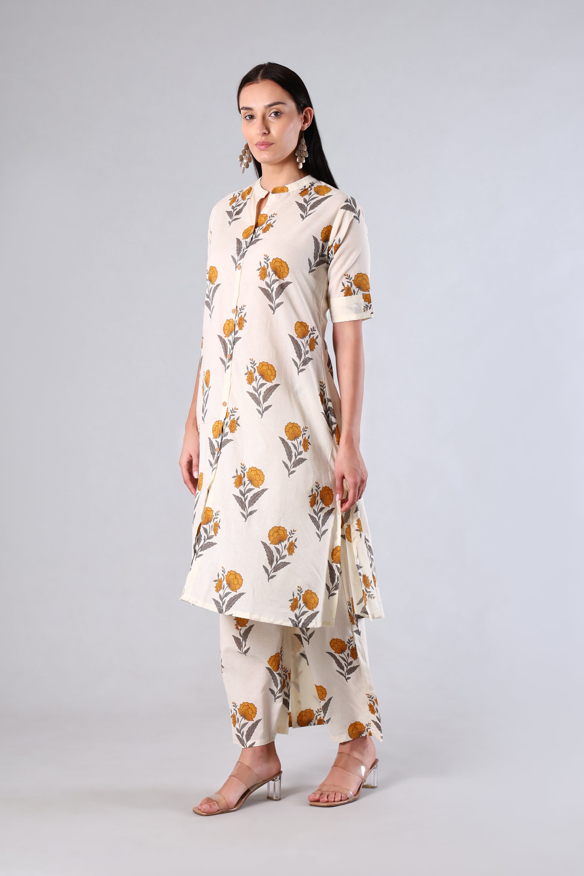 Woman wearing a Yellow -colored kurta with floral patterns on a gray background