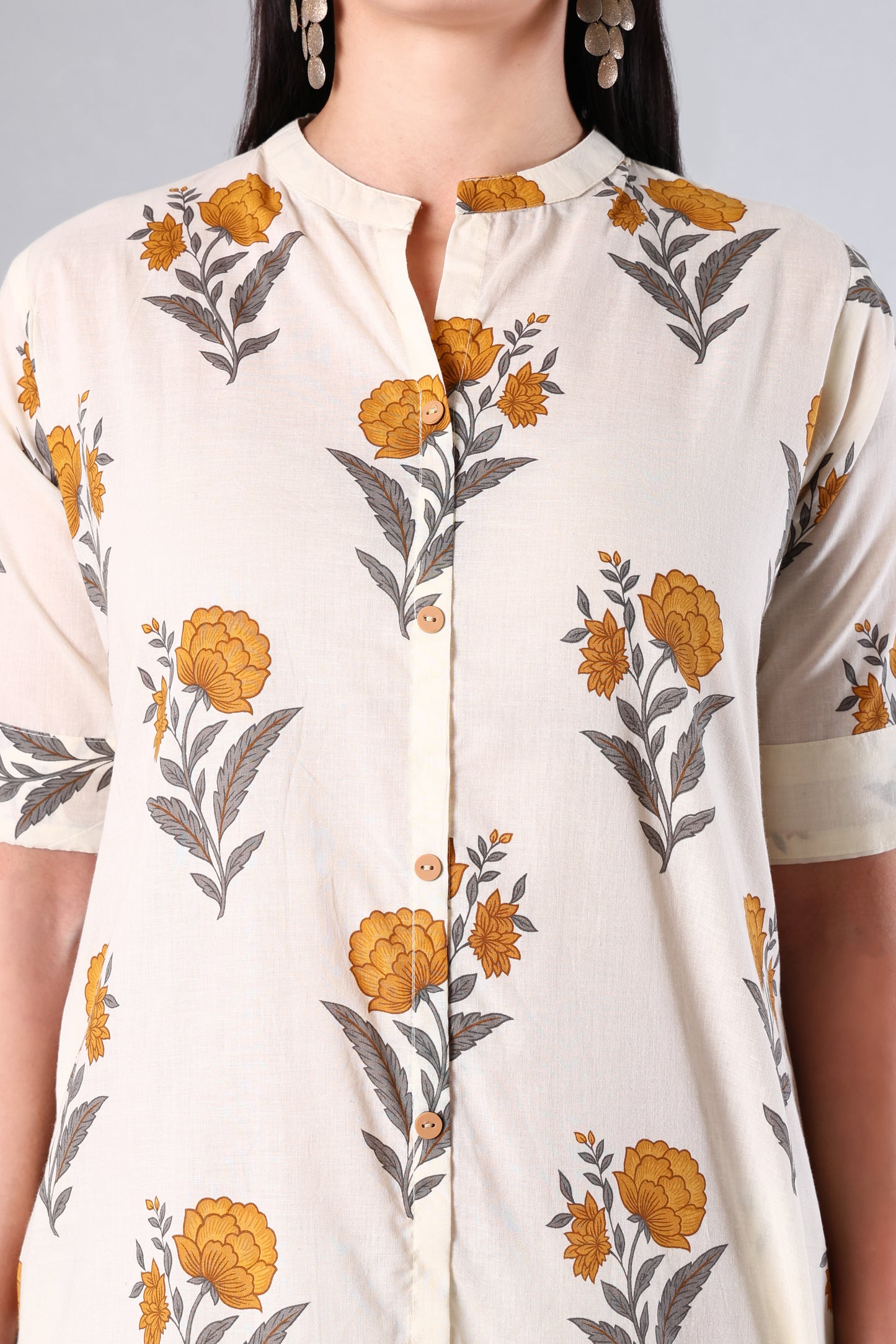 Woman wearing a white blouse with Yellow floral patterns on a plain background