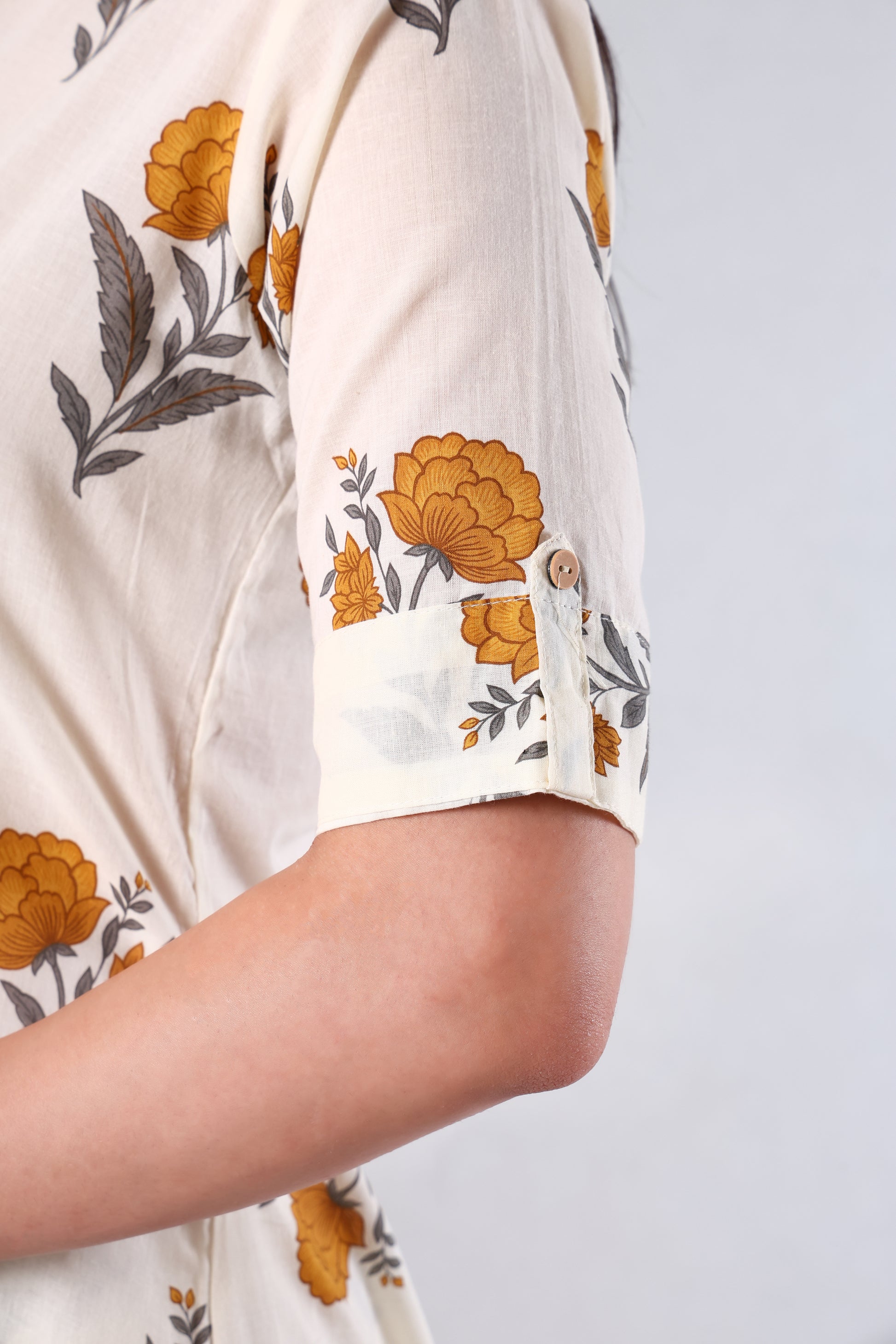 Close-up of a person wearing a white shirt with Yellow floral patterns on a light gray background