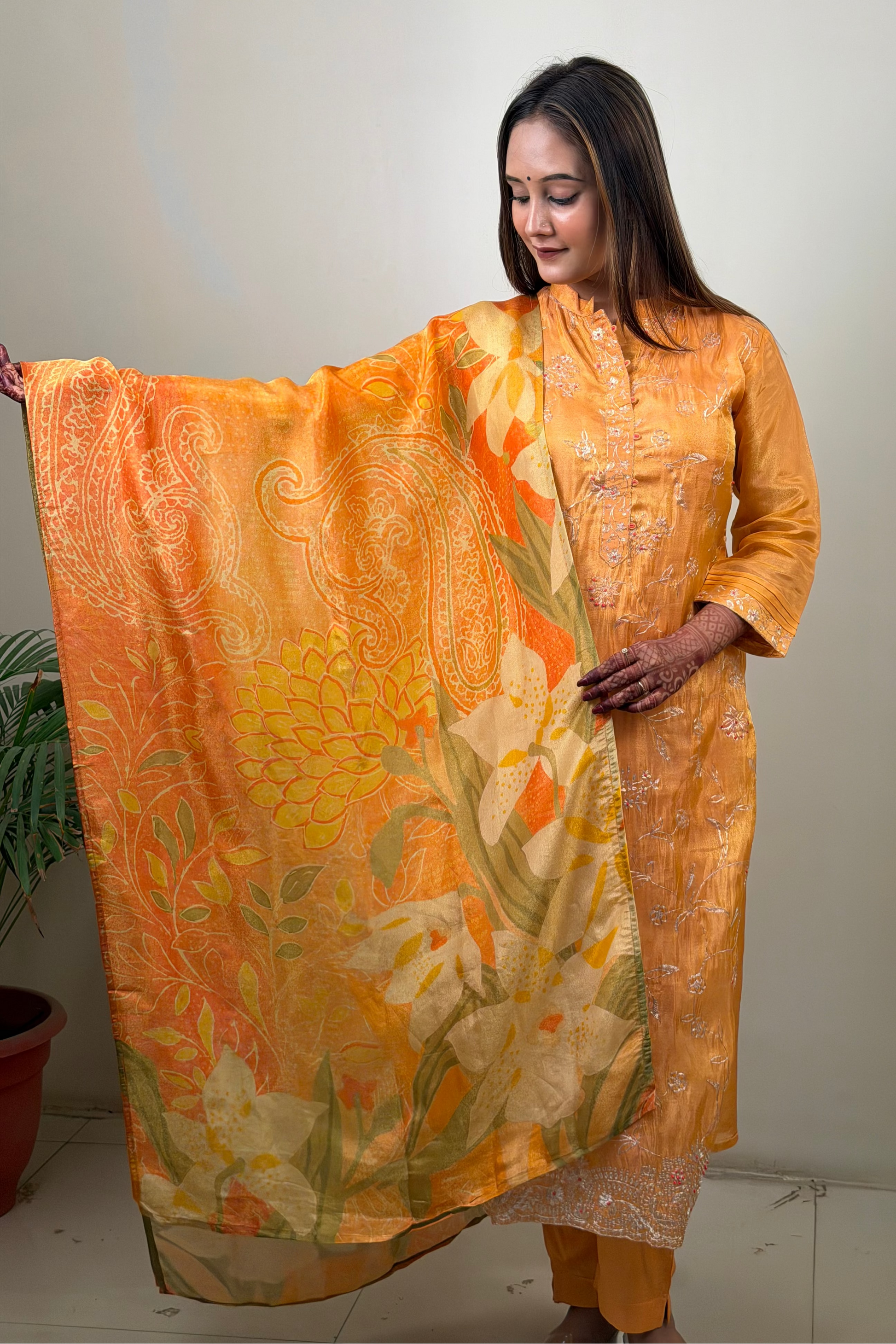Woman holding a large orange floral fabric against a plain background