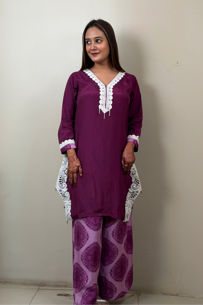 Woman wearing a purple traditional outfit with white lace details against a plain background