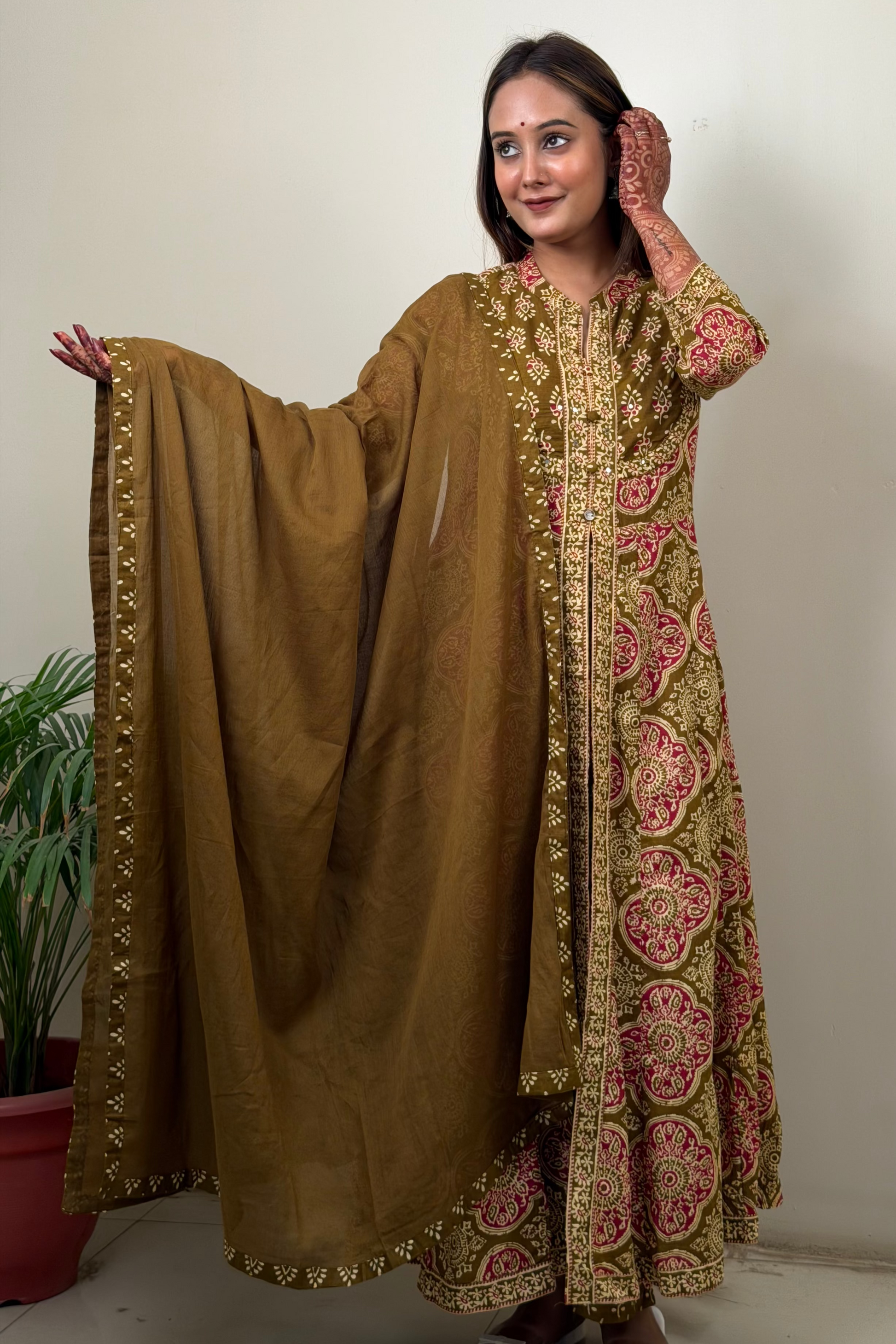 Woman wearing a traditional brown and pink embroidered outfit with a matching dupatta.