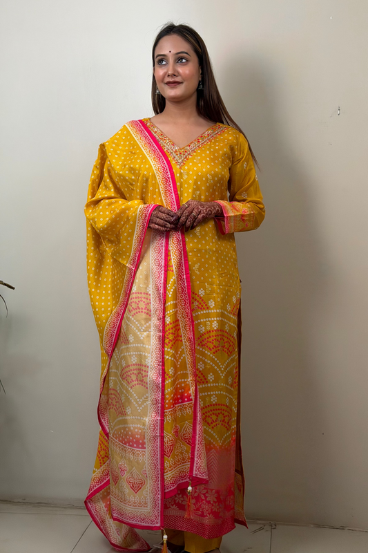 Woman wearing a yellow traditional outfit with pink and white patterns against a plain background