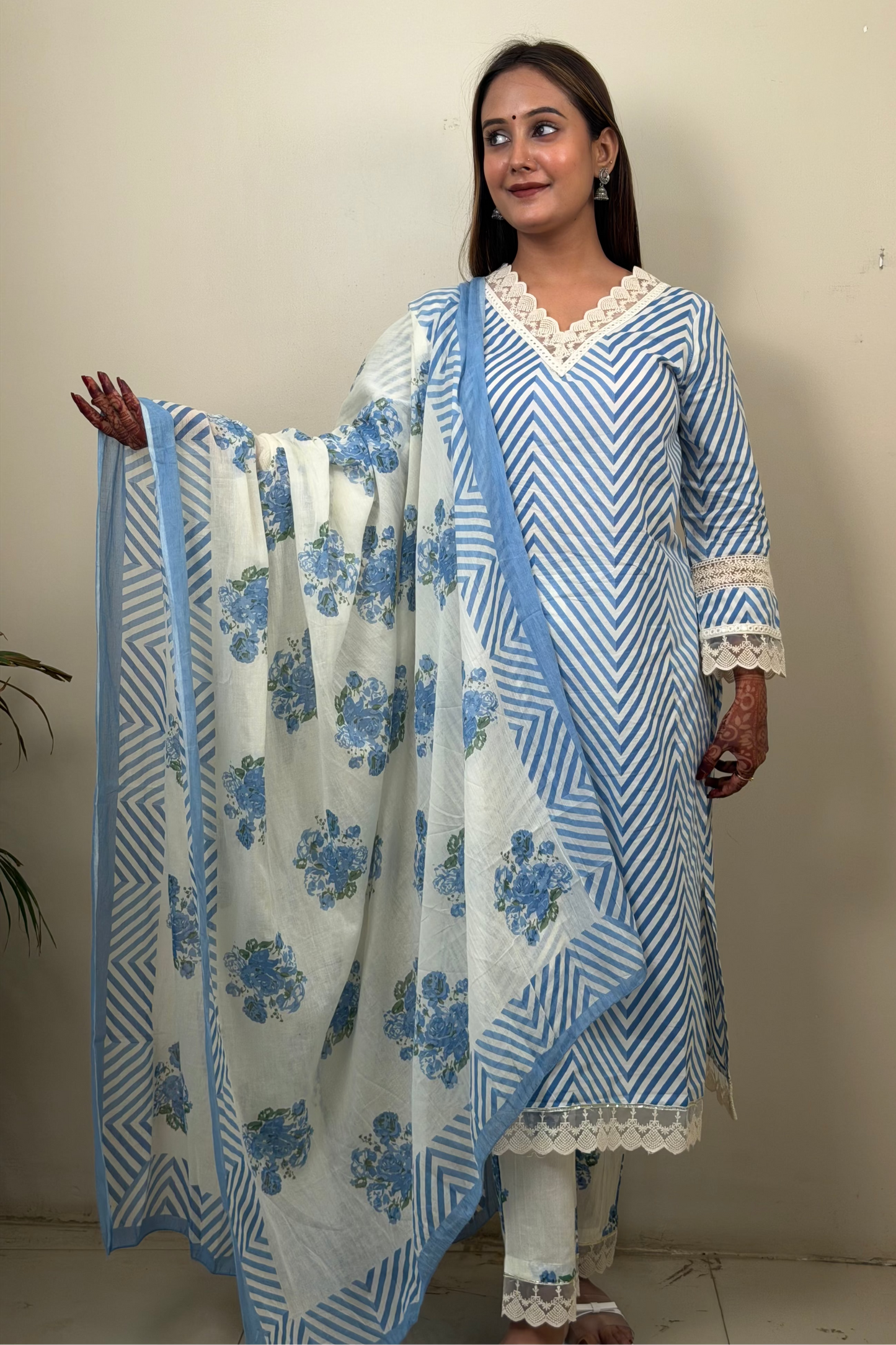 Woman holding a blue and white floral dupatta against a plain background