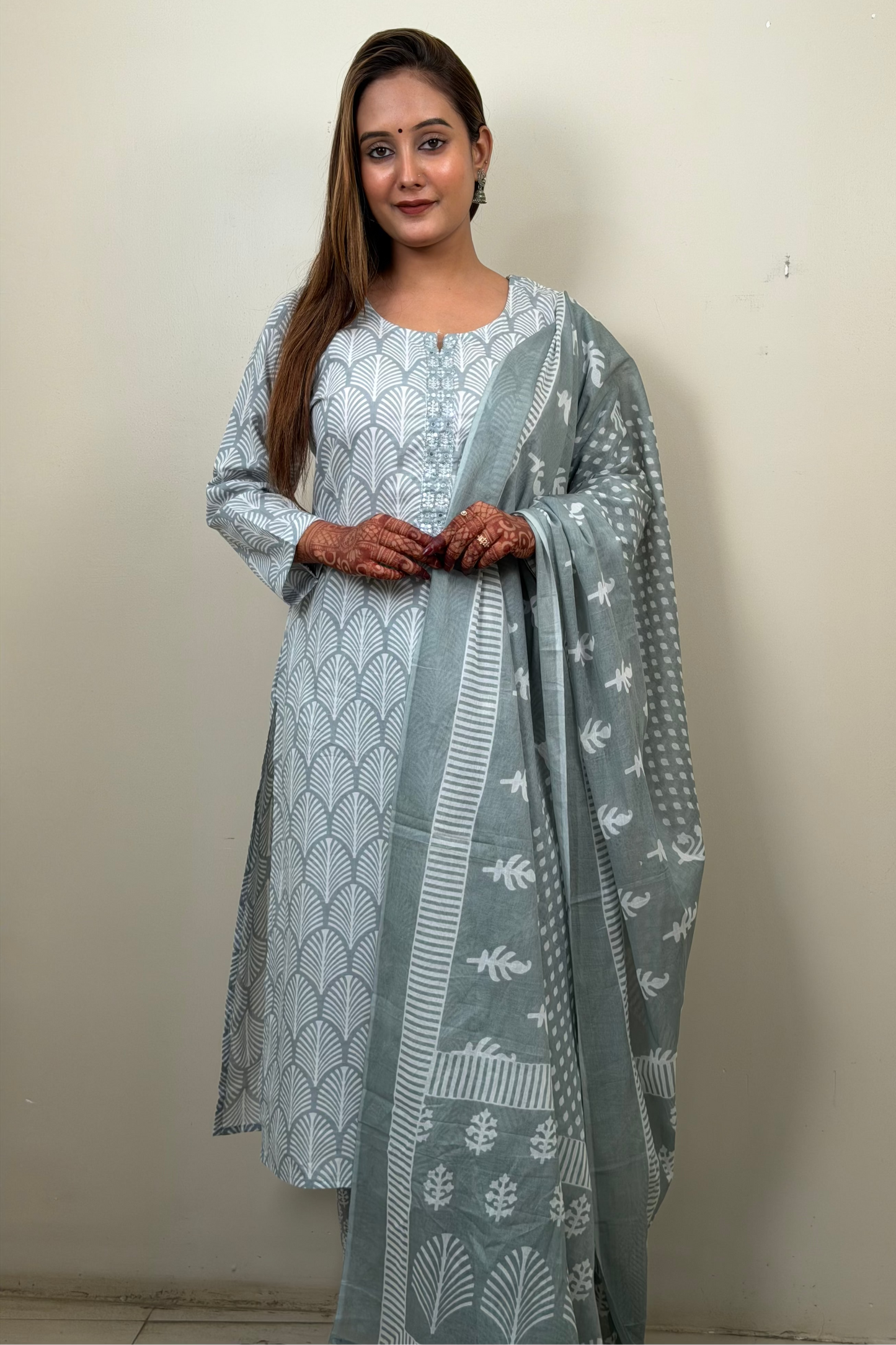 Woman wearing a light blue traditional outfit with a matching dupatta against a plain background