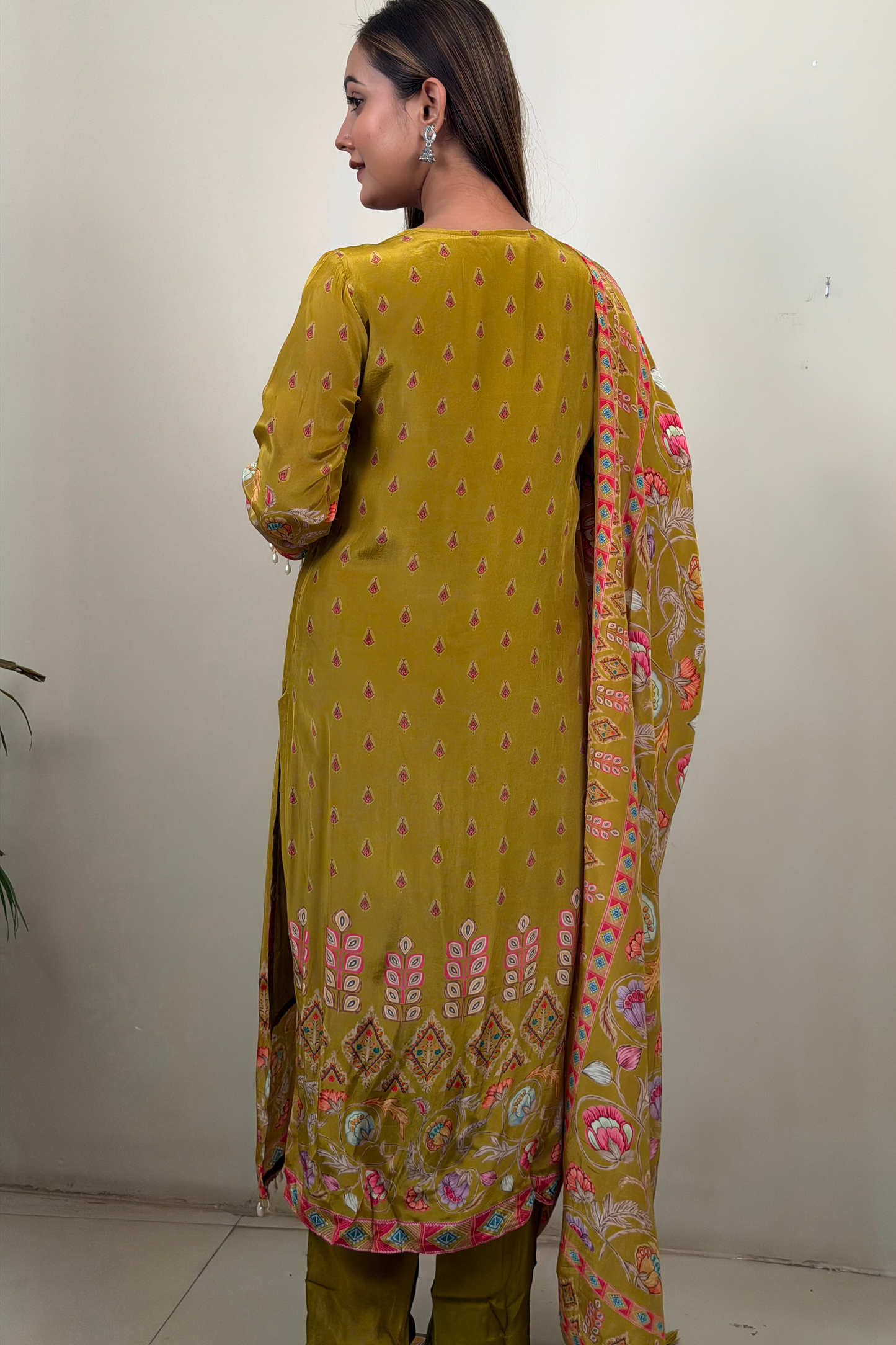 Woman wearing a mustard yellow traditional outfit with a floral dupatta against a white background