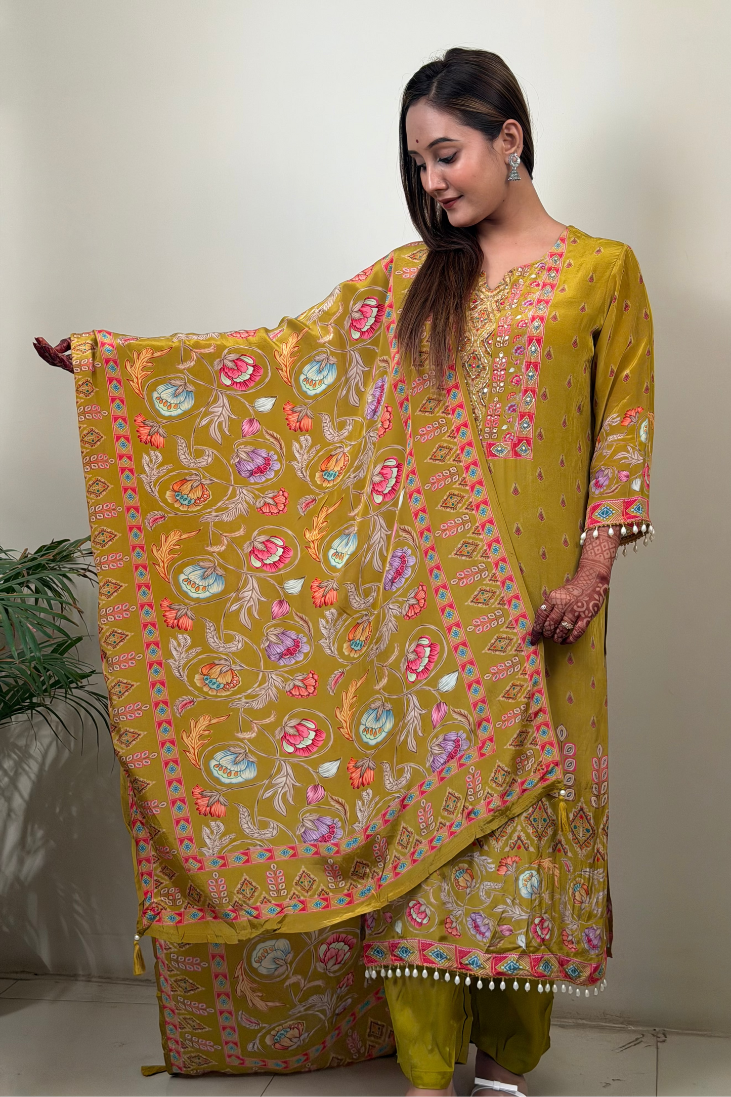 Woman wearing a yellow traditional outfit with a floral dupatta against a white background