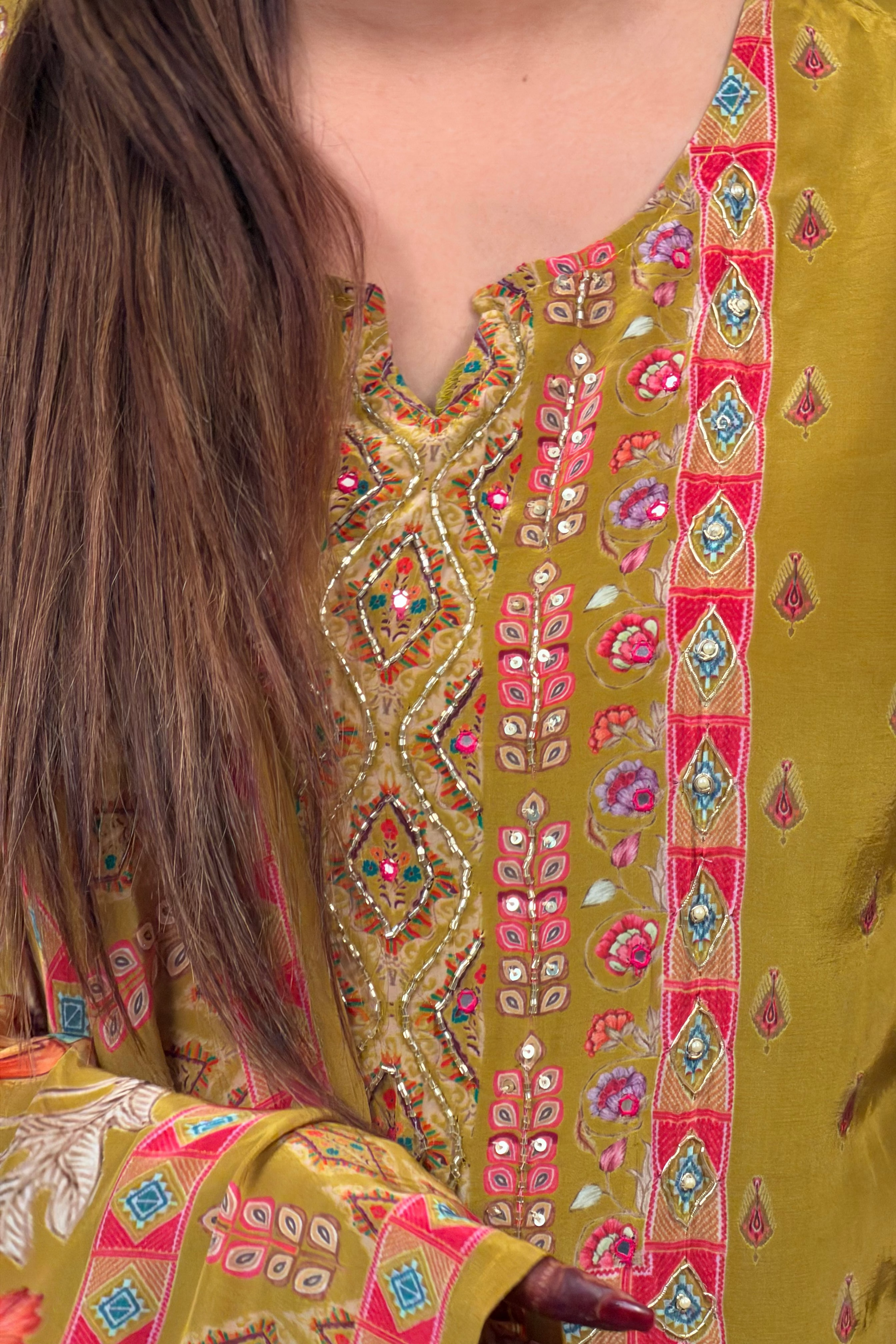 Close-up of a person wearing a traditional embroidered garment with intricate patterns.