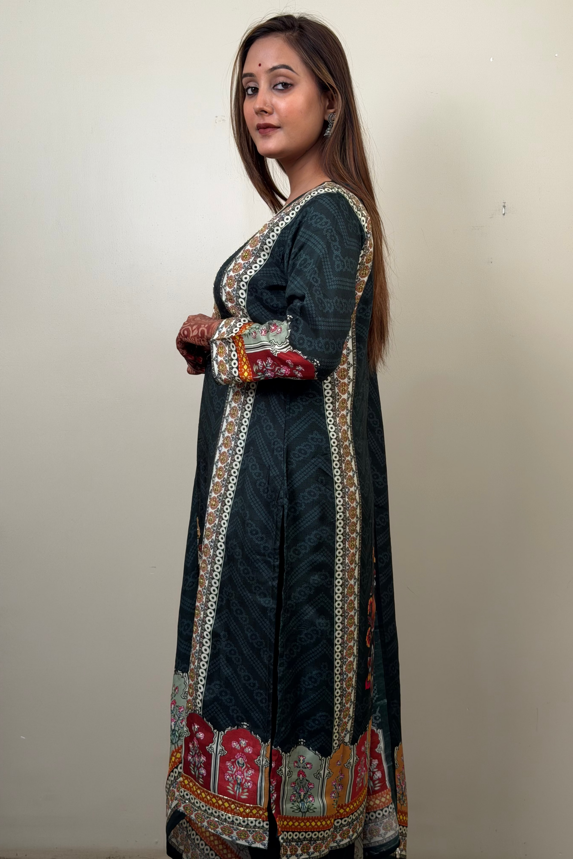 Woman wearing a dark blue traditional outfit with colorful embroidery on a plain background