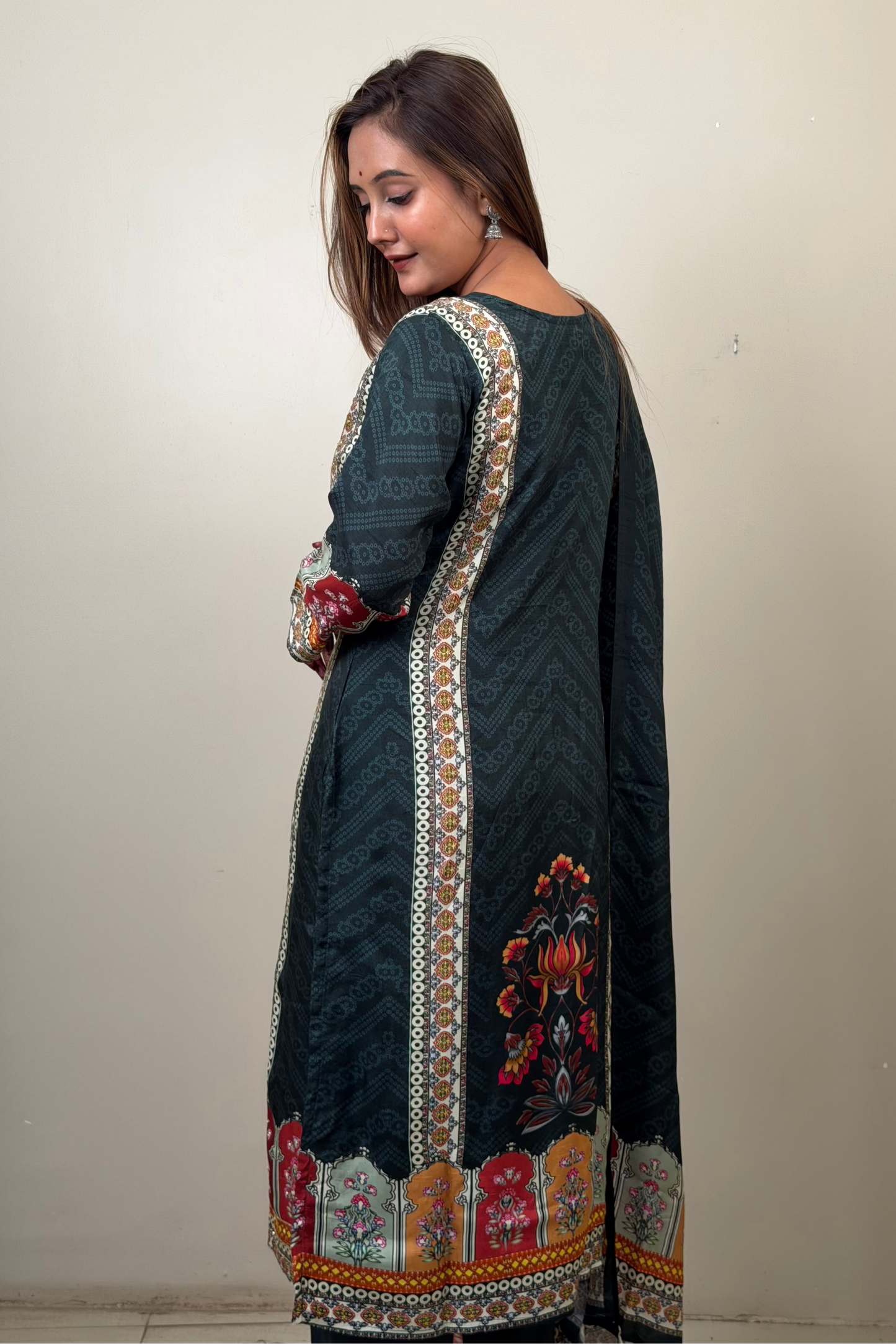 Woman wearing a dark green embroidered traditional outfit against a plain background