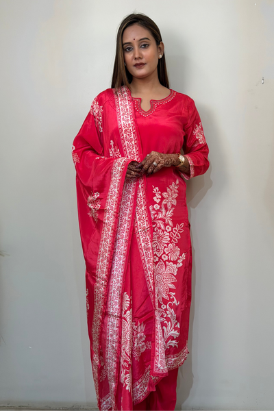 Woman wearing a red traditional outfit with white patterns against a plain background