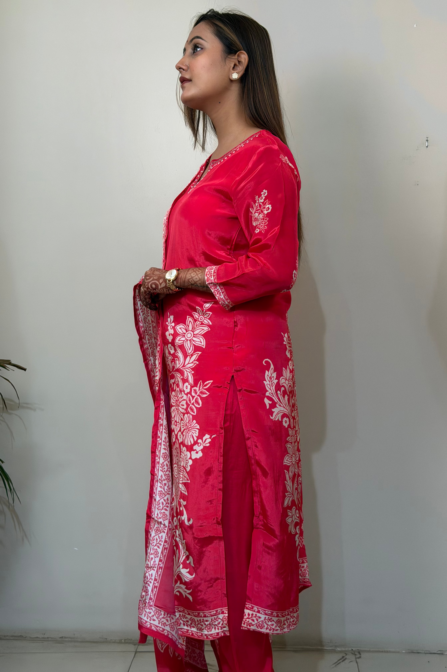 Woman wearing a red traditional outfit with white patterns against a plain background