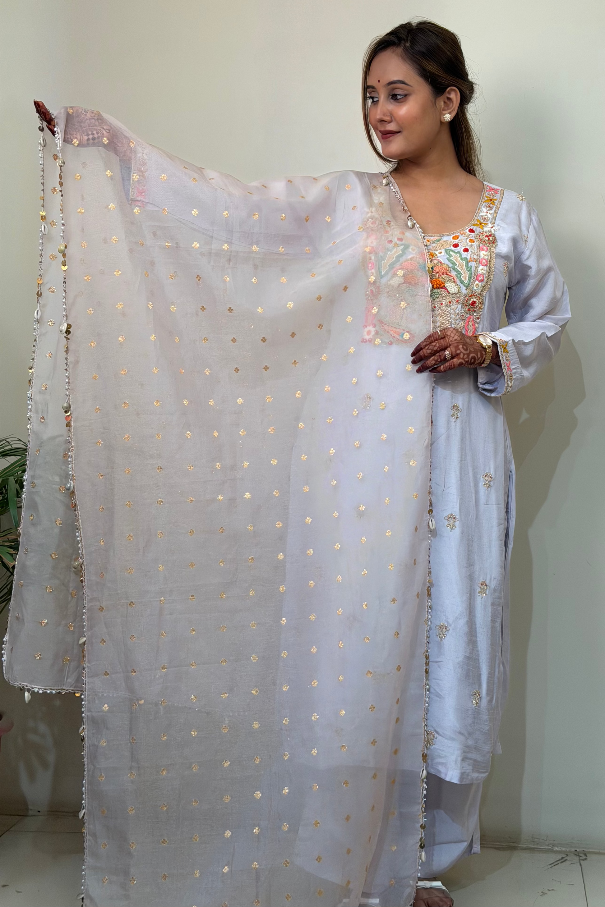 Woman in a lavender traditional outfit with a sheer dupatta against a plain background