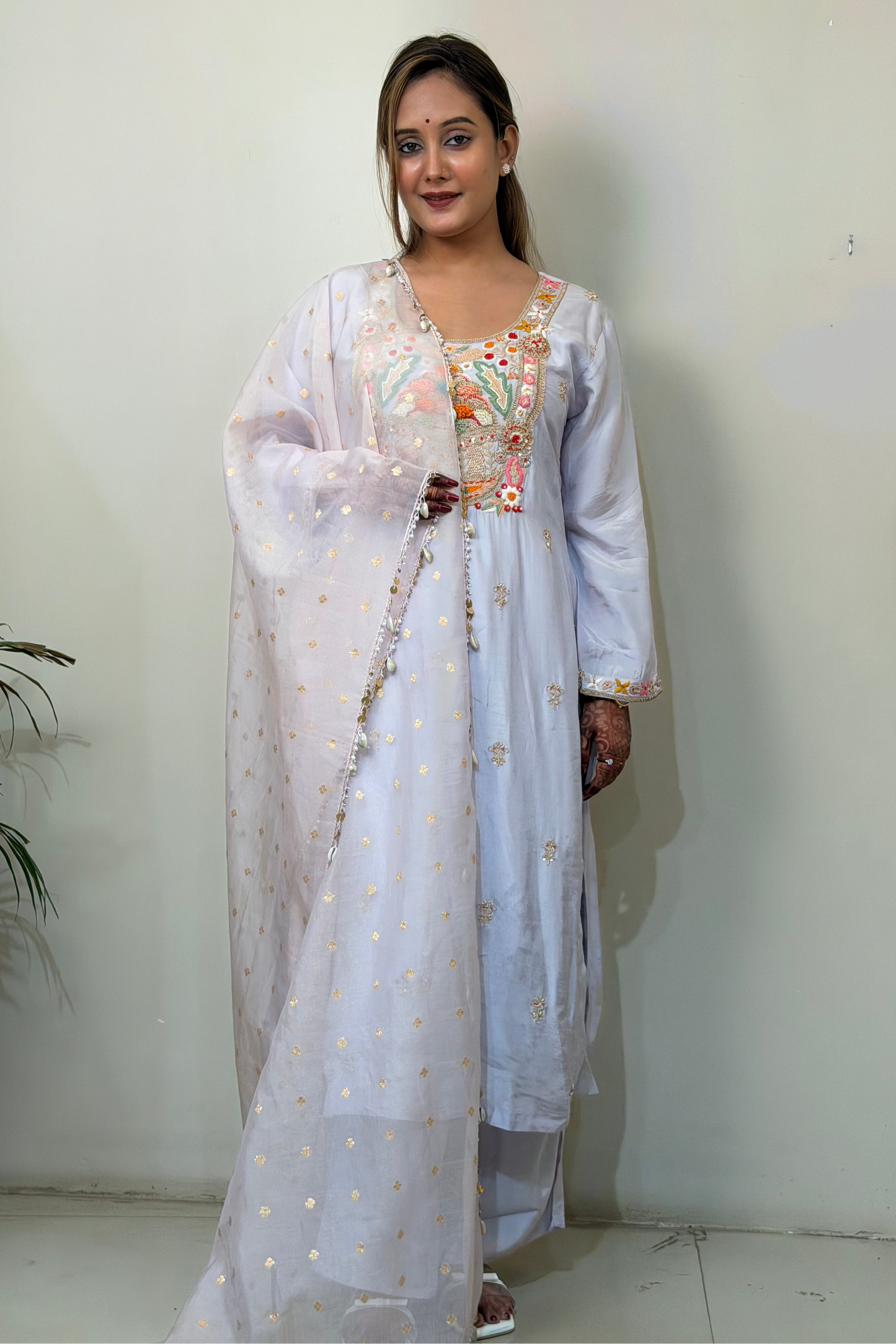 Woman wearing a light blue traditional outfit with a white dupatta against a plain background