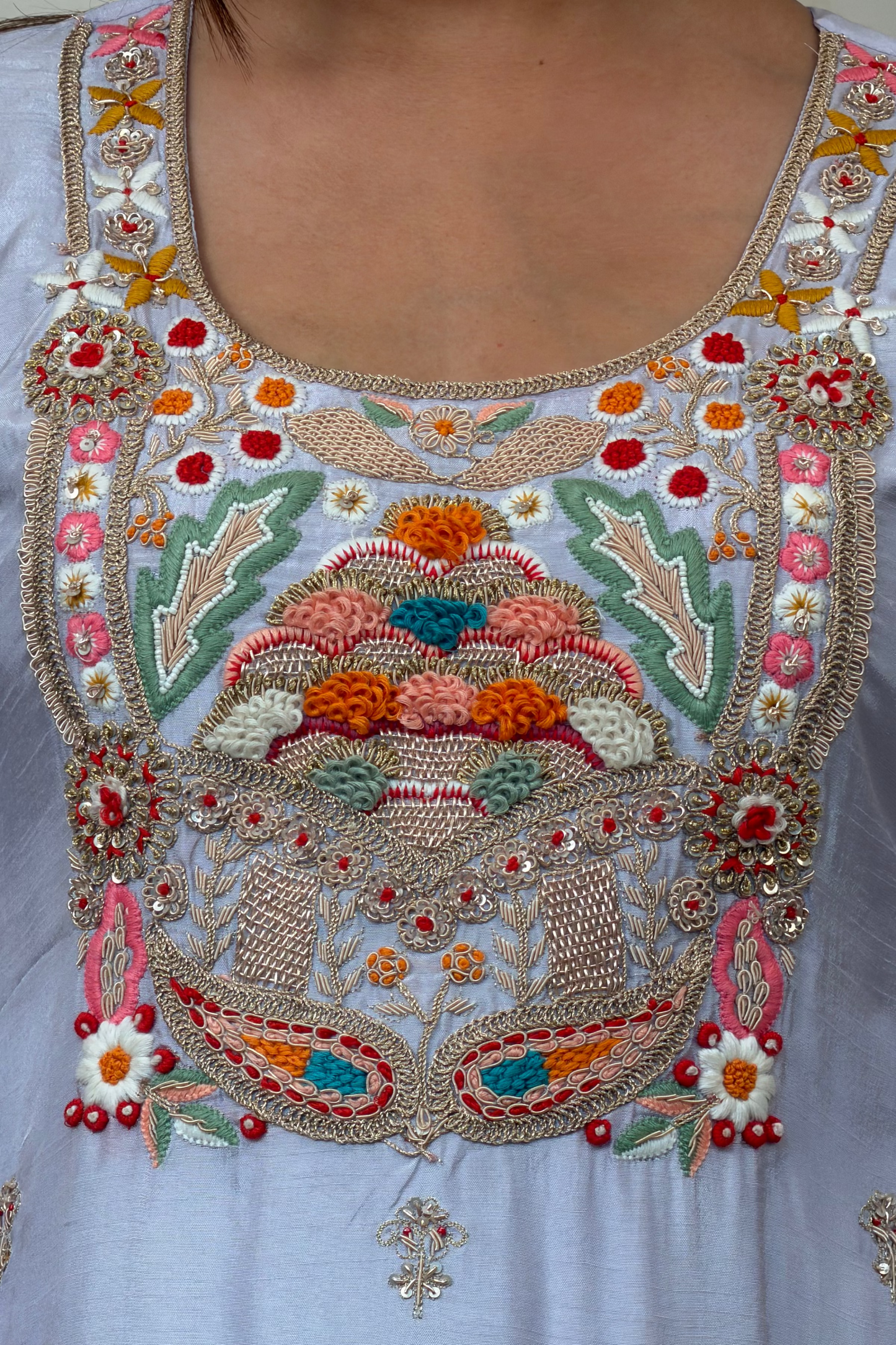 Close-up of a embroidered garment with colorful patterns on a light blue background
