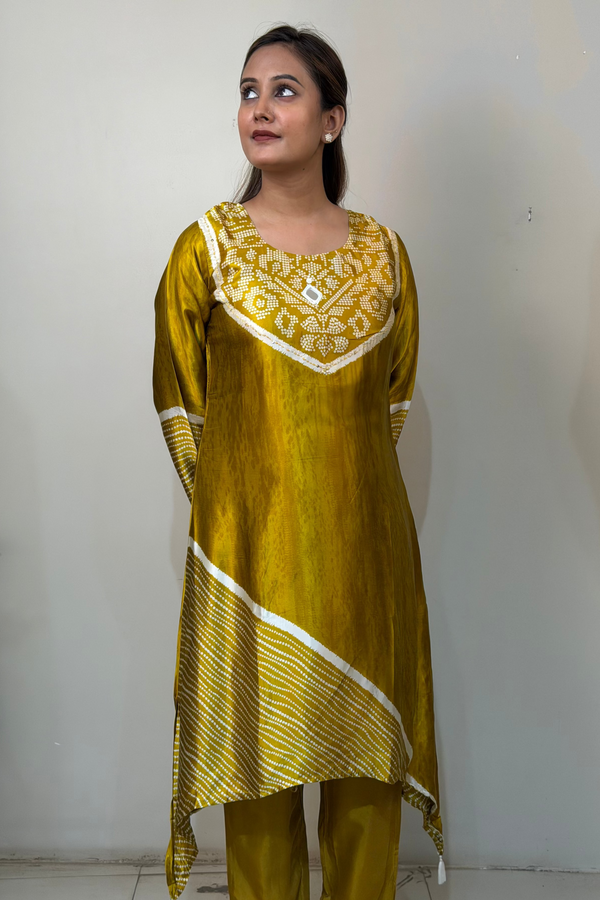 Woman wearing a yellow traditional outfit with white patterns against a plain wall.