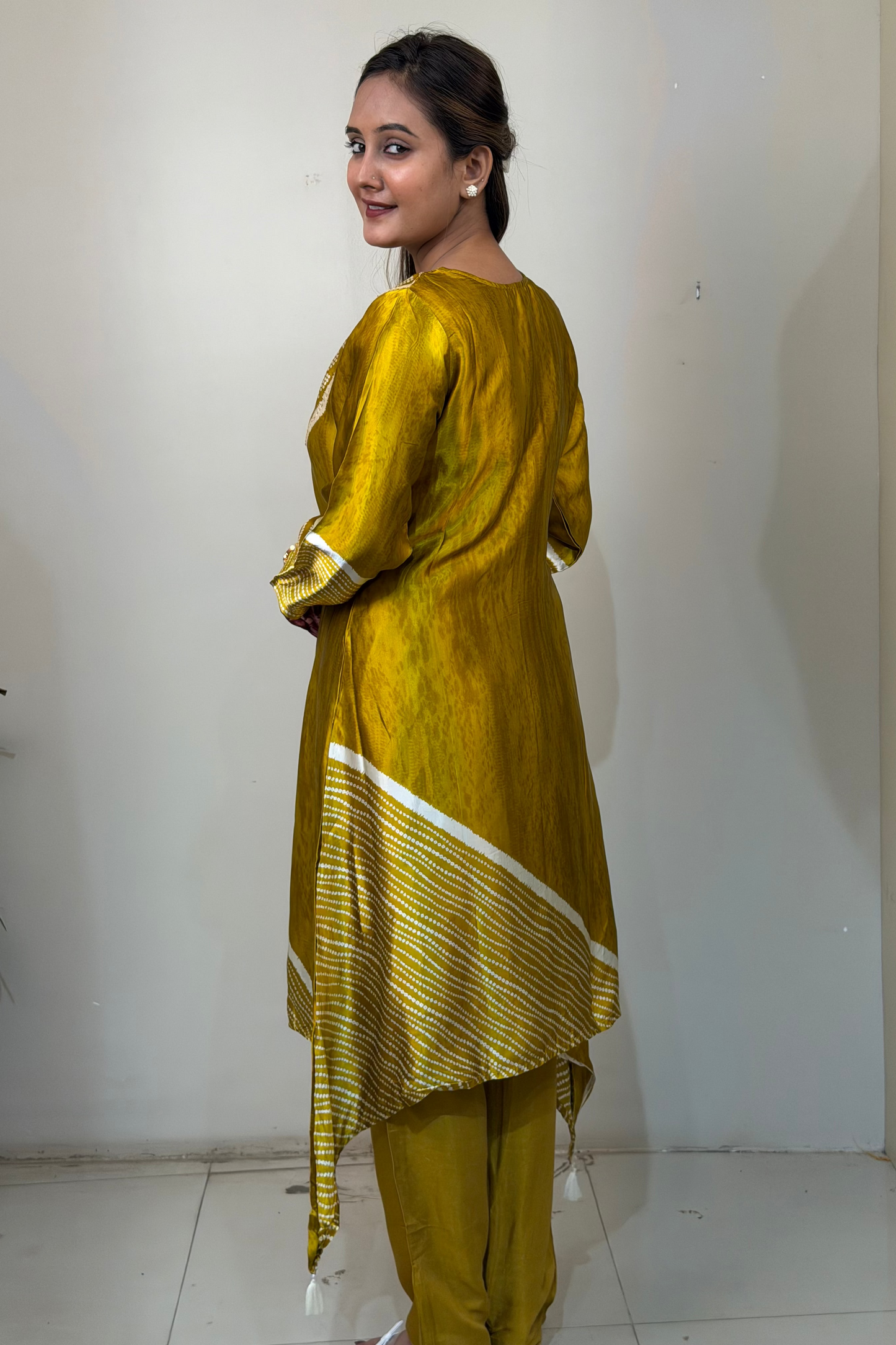 Woman wearing a yellow traditional outfit with white stripes in a minimal indoor setting
