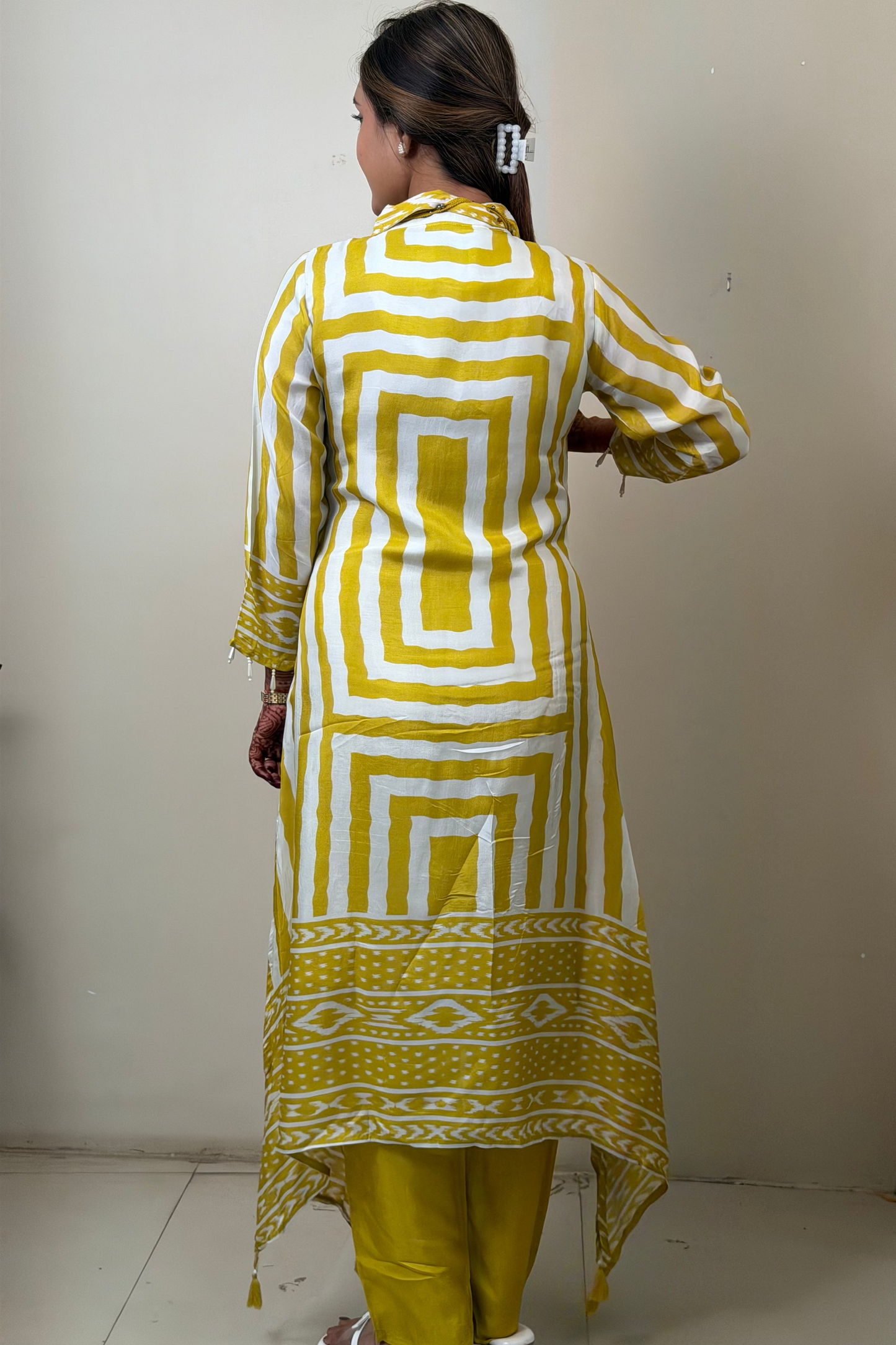 Woman wearing a yellow and white patterned kurta with yellow pants in front of a mirror.