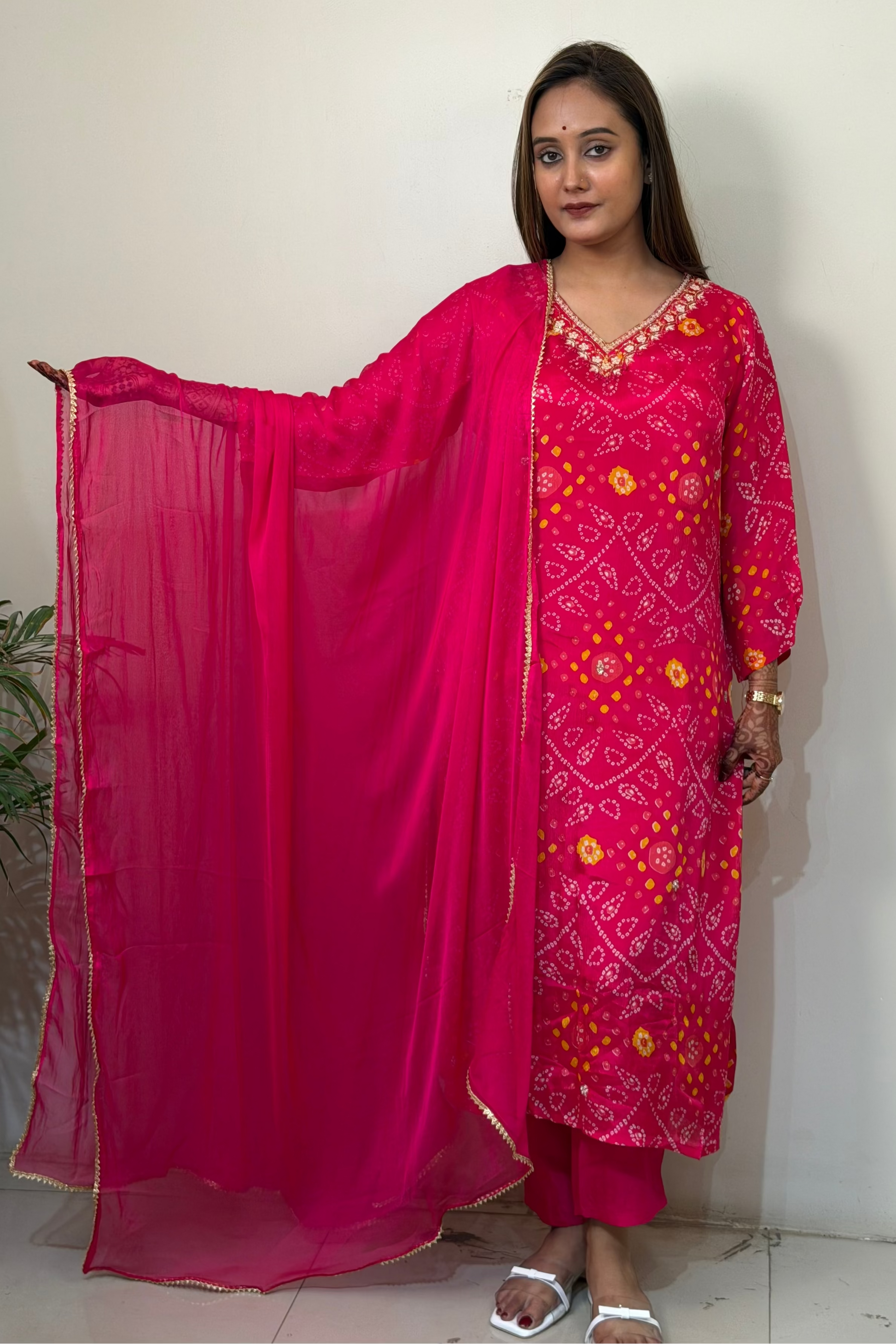 Woman wearing a pink traditional outfit with a matching dupatta against a white background