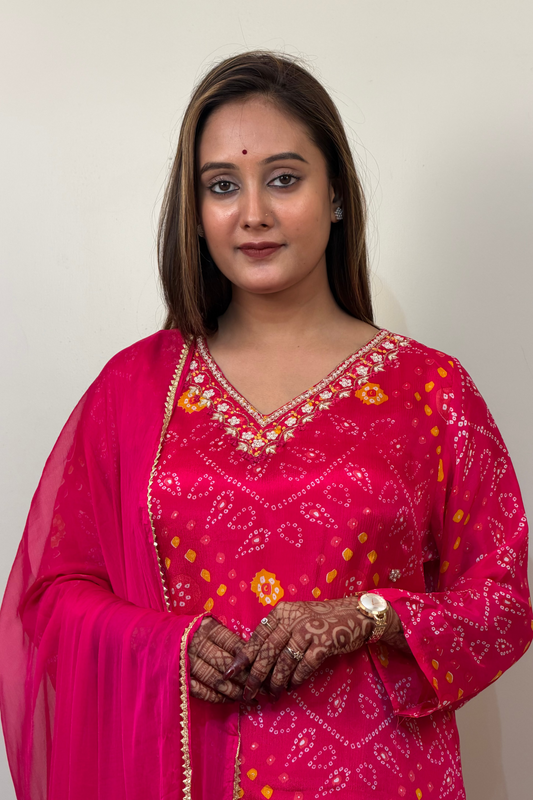 Woman wearing a pink traditional outfit with intricate designs on a plain background
