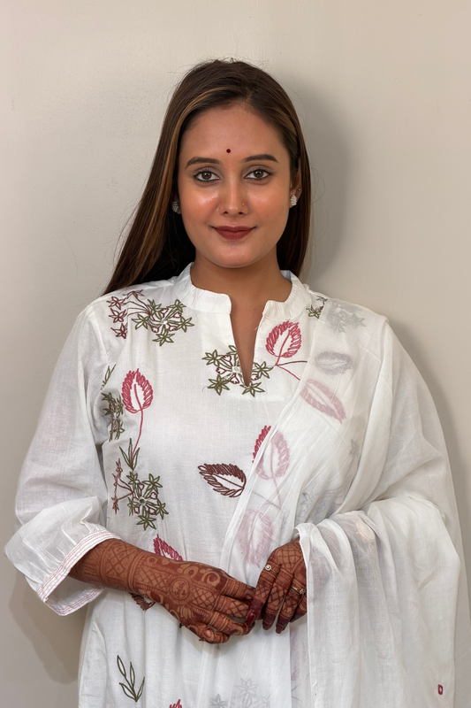 Woman wearing a white embroidered traditional outfit against a plain background
