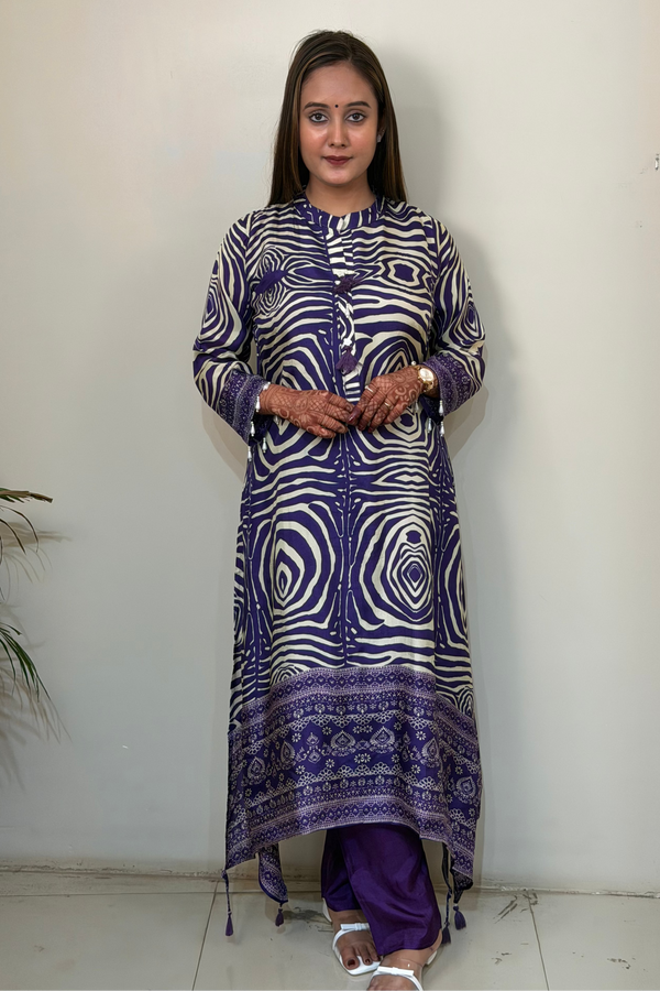 Woman wearing a patterned purple and white kurta against a plain background