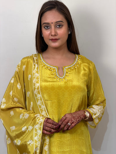 Woman wearing a yellow traditional outfit with white patterns on a plain background