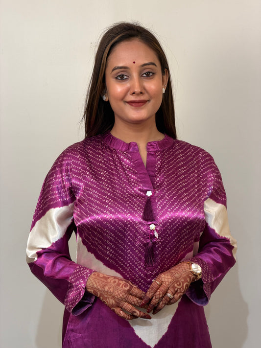 Woman wearing a purple and white traditional outfit against a plain background